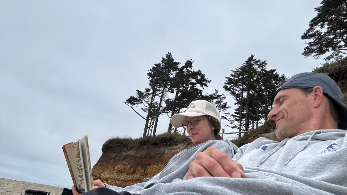 Jarod and Rachel relaxing together and reading at the beach
