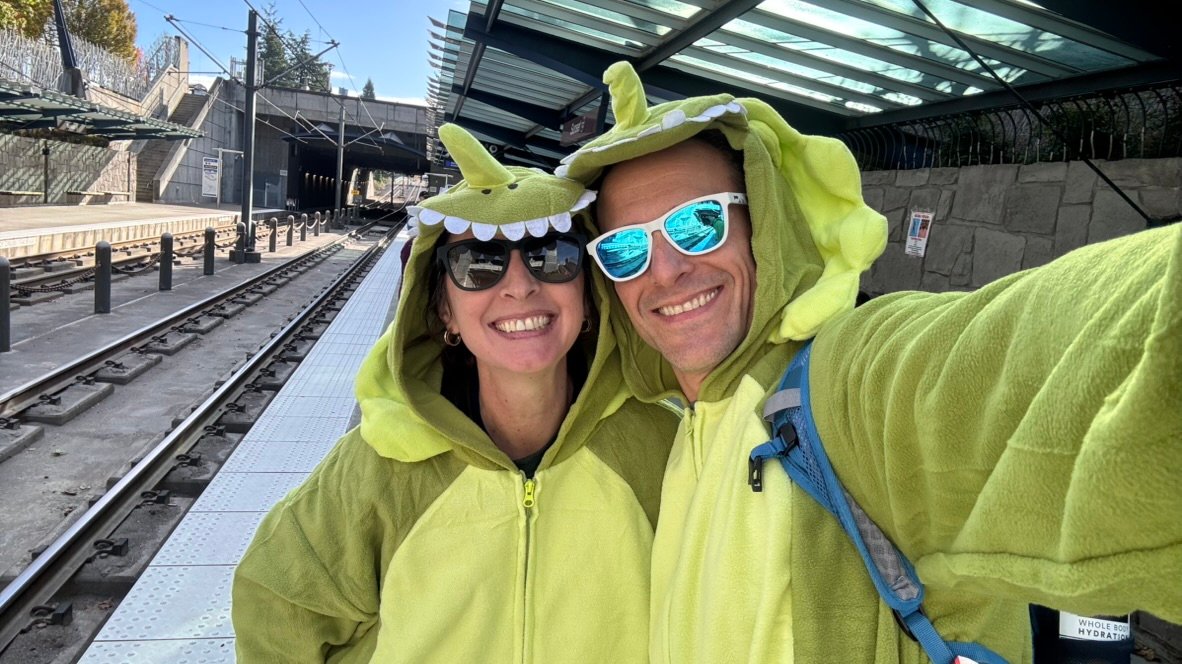 Jarod and Rachel smiling together in playful green dinosaur costumes
